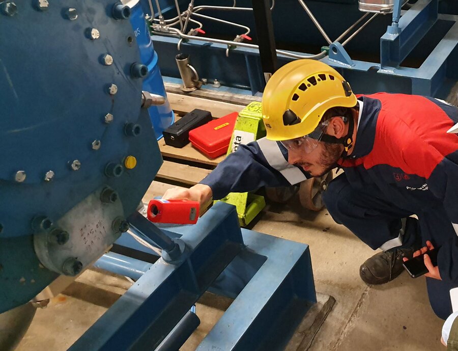 Compressor assessment by technician kneeling in front of compressor