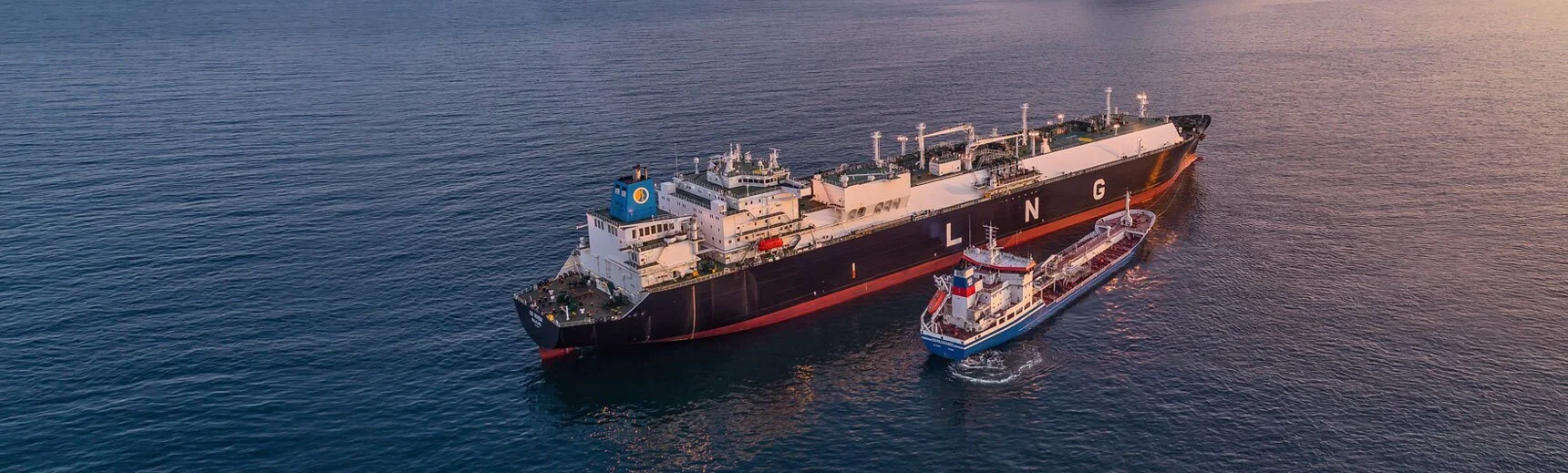 LNG tanker on sea next to tuckboat