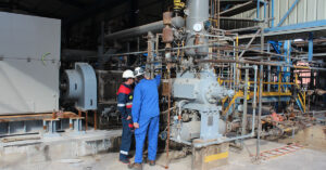 Two engineers standing in front of compressor system on customer site